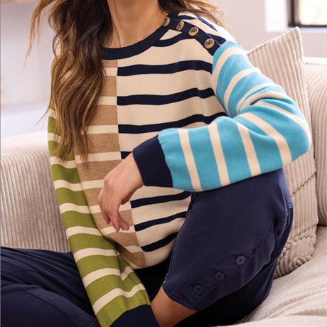 Person wearing a colorful striped sweater sitting on a couch.