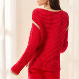 Red sweater with gold trim on a neutral background