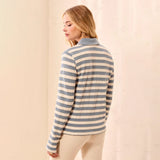 A woman wearing a long-sleeve knit polo-style top with horizontal blue-gray and cream stripes, shown from the back against a soft beige backdrop.