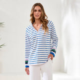 Woman wearing a blue and white striped shirt with colorful cuffs against a white background