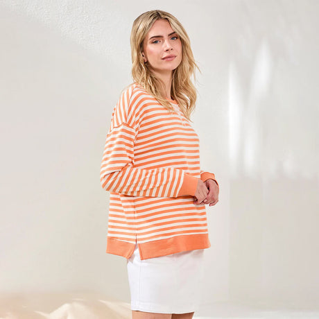 Woman wearing an orange and white striped sweater against a plain background