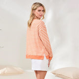 Woman wearing an orange and white striped sweater in a minimalistic setting