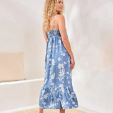 Woman wearing a blue floral dress in a minimal indoor setting