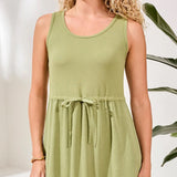 Woman wearing a green dress with a plant in the background