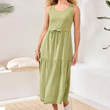 Woman wearing a green dress in a minimalistic room with plants.