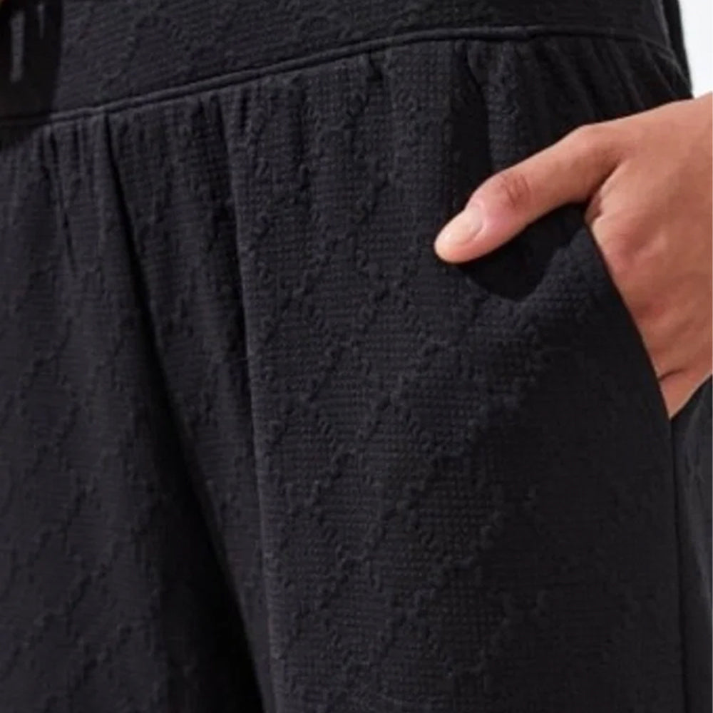Close-up of a textured black fabric with a hand pointing to it