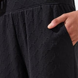 Close-up of a textured black fabric with a hand pointing to it
