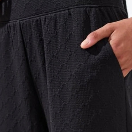 Close-up of a textured black fabric with a hand pointing to it