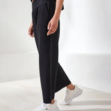 Person wearing black pants and white sneakers on a white background