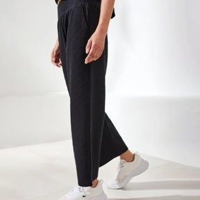 Person wearing black pants and white sneakers on a white background