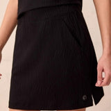 Black skirt worn by a person on a beige background