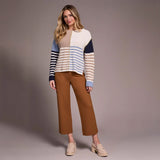 Woman wearing a striped sweater and brown pants against a plain background
