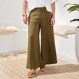 Person wearing olive green wide-leg pants in a minimal indoor setting