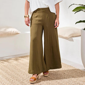Person wearing olive green wide-leg pants in a minimal indoor setting