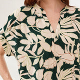 Person wearing a green dress with beige floral pattern on a white background