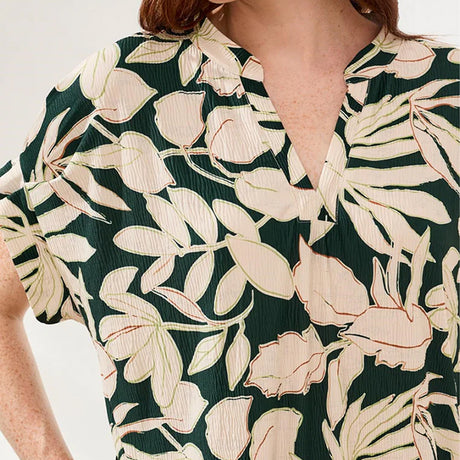 Person wearing a green dress with beige floral pattern on a white background