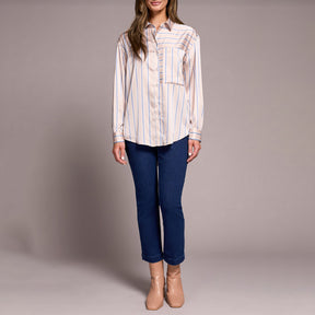 Woman wearing a striped shirt and blue jeans against a plain background