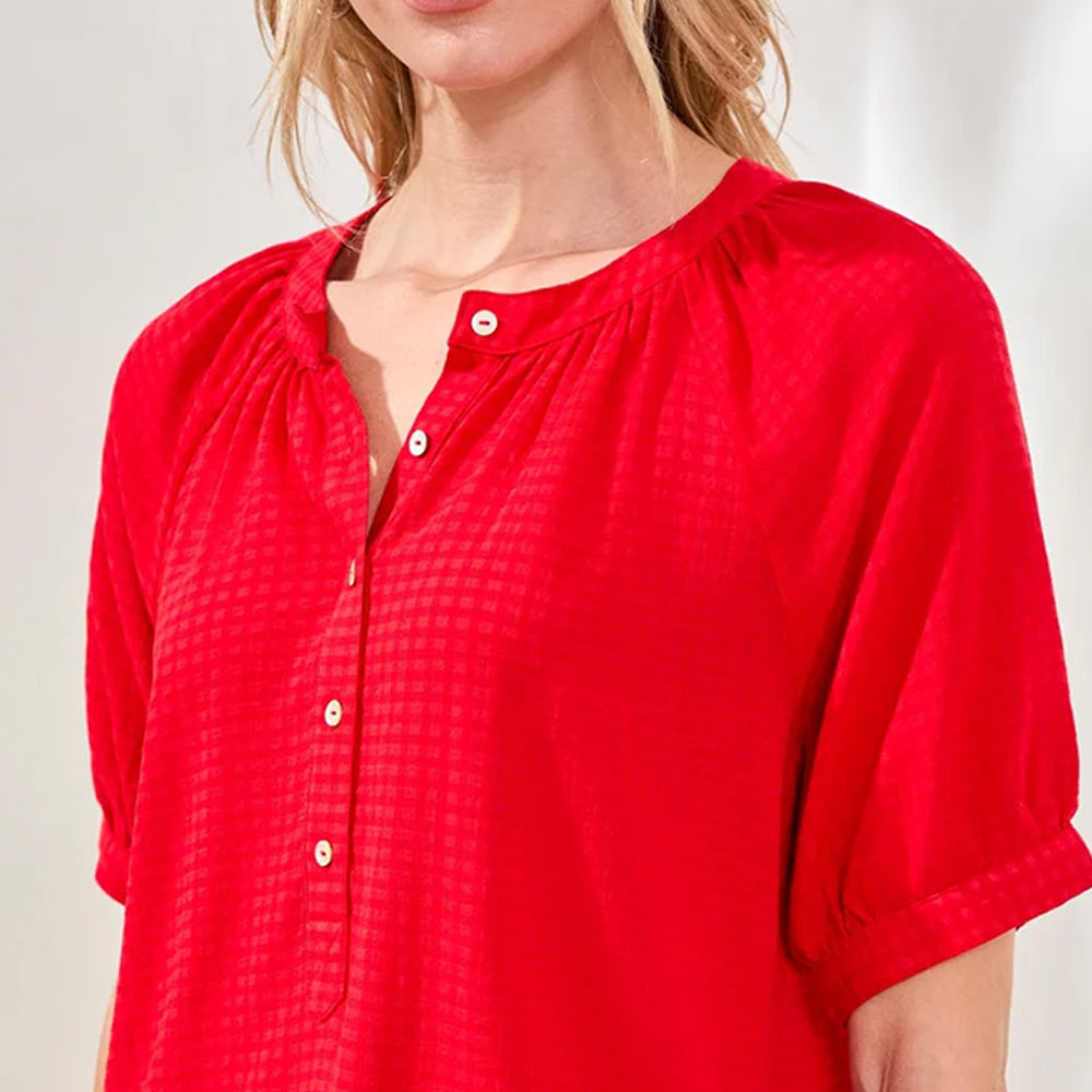 Red blouse with a textured pattern worn by a person on a white background
