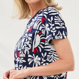 Woman wearing a navy blue scrub top with white floral pattern