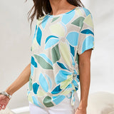 Woman wearing a colorful floral-patterned top against a white background