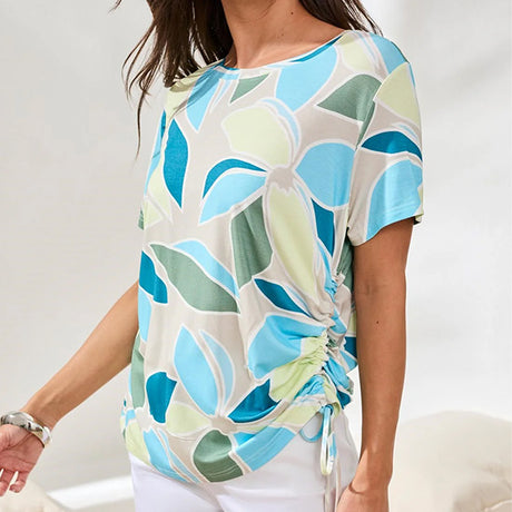 Woman wearing a colorful floral-patterned top against a white background