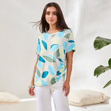Woman wearing a colorful leaf-patterned shirt in a minimalistic setting
