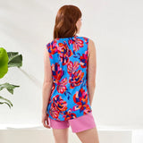 Woman wearing a colorful floral sleeveless top and pink shorts on a white background