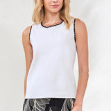 Woman wearing a white sleeveless top with black trim on a plain background