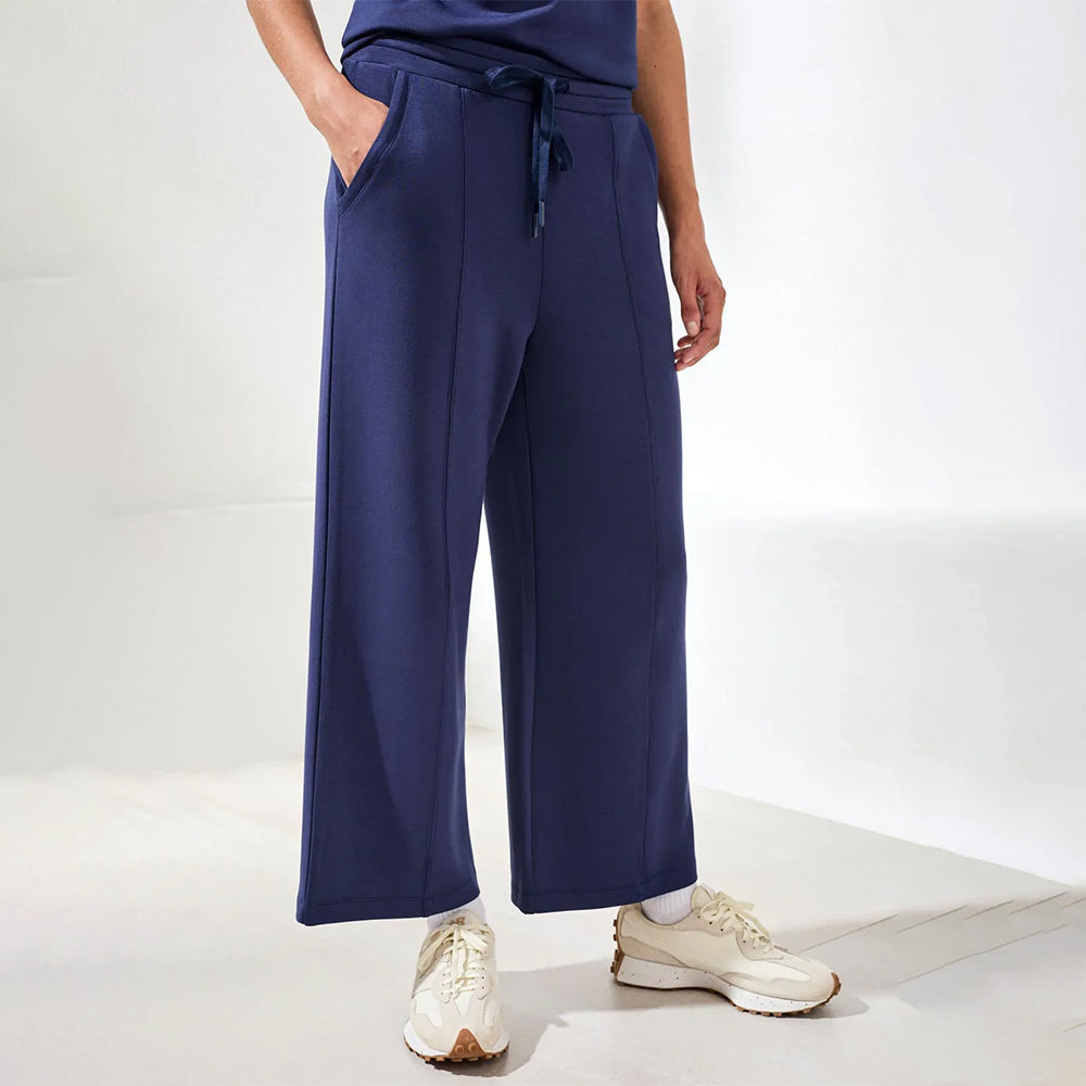 Person wearing navy wide-leg pants and white sneakers on a white background