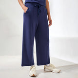 Person wearing navy wide-leg pants and white sneakers on a white background