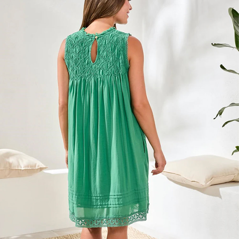 Woman wearing a green lace dress in a minimal indoor setting