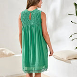 Woman wearing a green lace dress in a minimal indoor setting