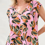Woman wearing a pink dress with colorful floral pattern on a plain background