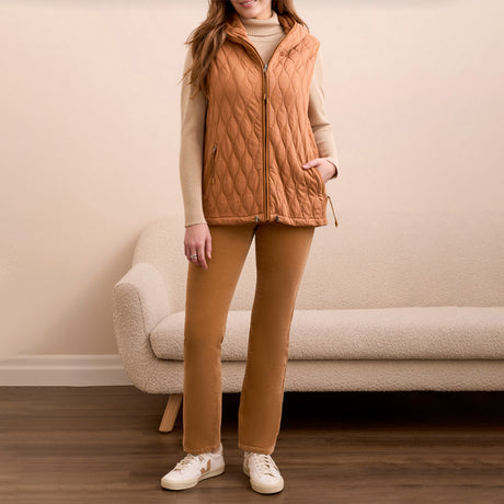 Woman wearing a wheat colored vest over a cream colored sweater with wheat colored pants.
