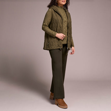 Woman wearing green zipper vest with brown pants and brown boots.