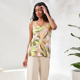 Woman wearing a patterned top and beige pants against a white background