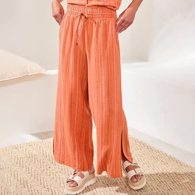 Person wearing orange striped pants with a white background