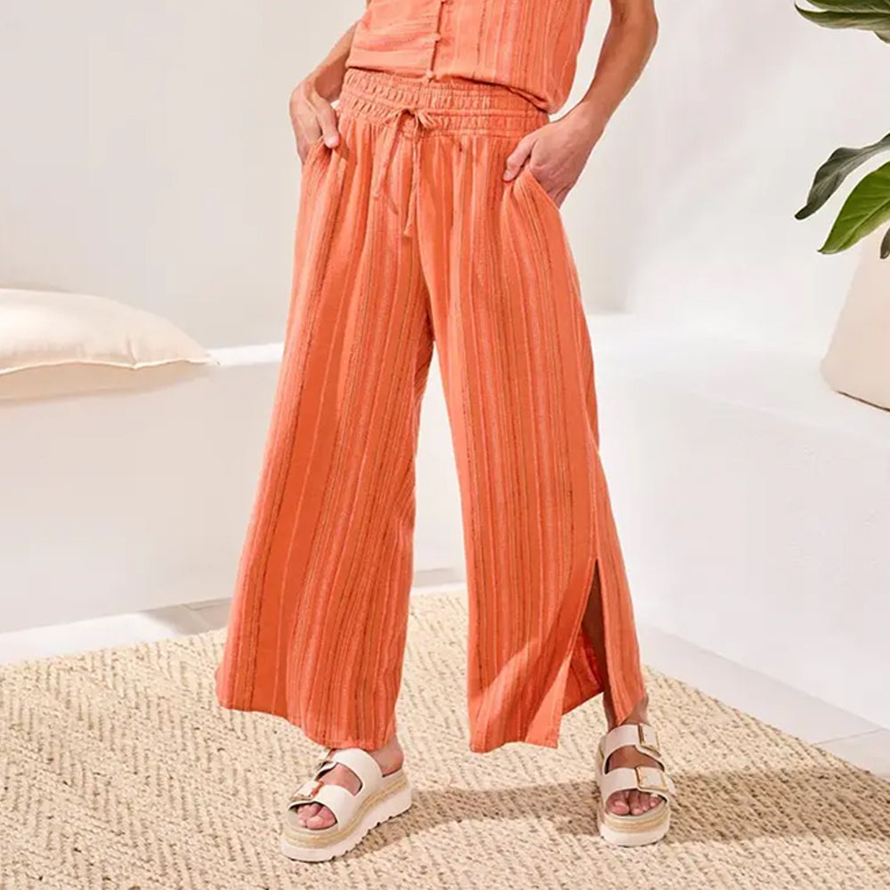 Person wearing orange striped pants and sandals in a home setting