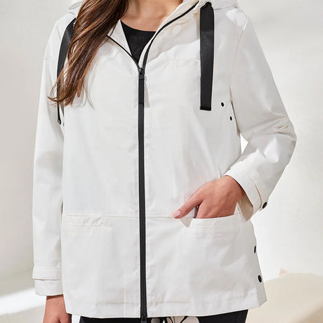 Person wearing a white raincoat with black accents on a plain background