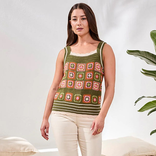 Woman wearing a patterned crochet tank top against a neutral background