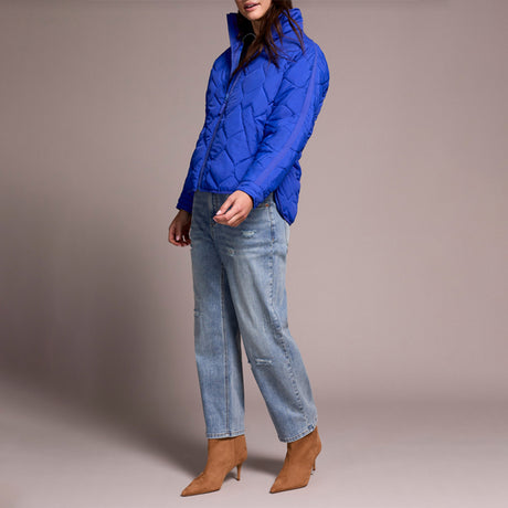 Person wearing a blue quilted jacket and jeans on a plain background