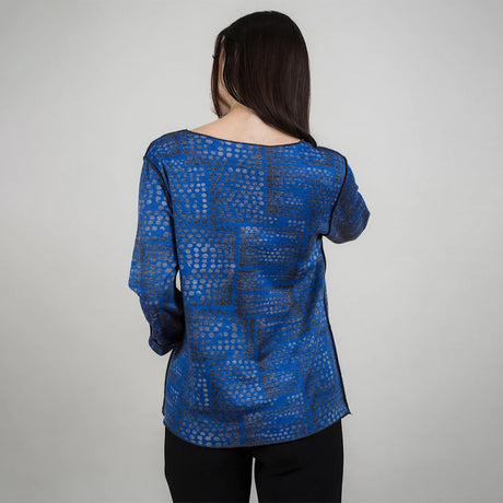 Woman wearing a blue patterned blouse against a gray background