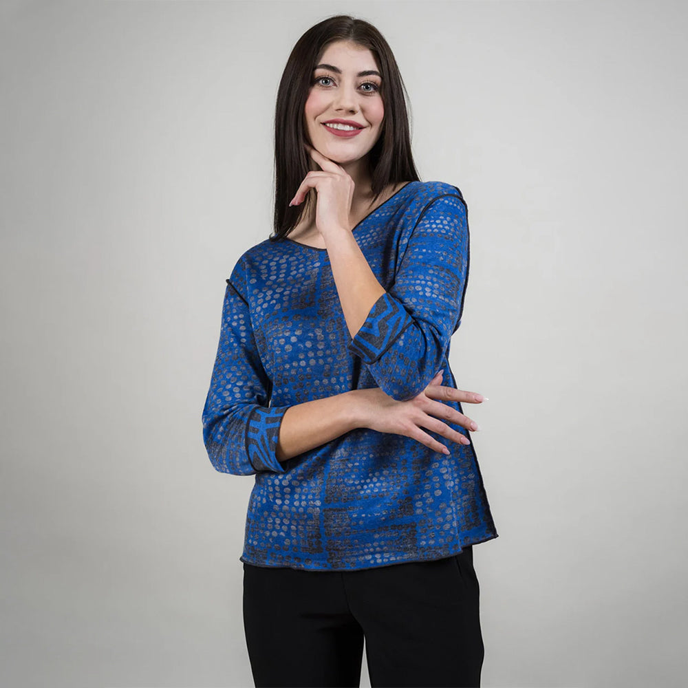 Woman wearing a blue patterned top against a gray background