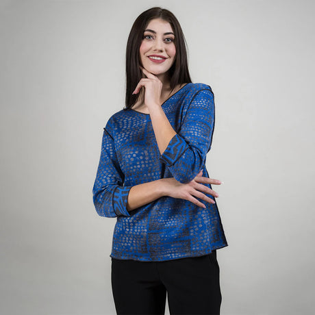 Woman wearing a blue patterned top against a gray background
