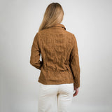 Person wearing a brown textured jacket and white pants on a plain background