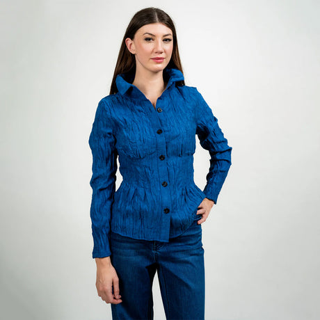 Woman wearing a blue textured shirt and jeans on a white background