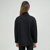 Person wearing a black coat against a plain background