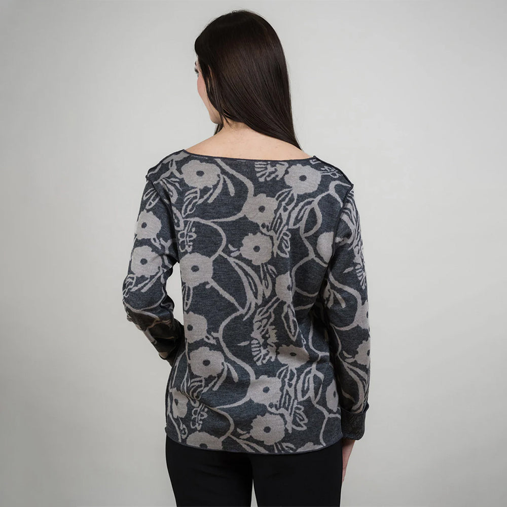 Woman wearing a floral patterned sweater against a plain background