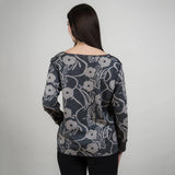 Woman wearing a floral patterned sweater against a plain background