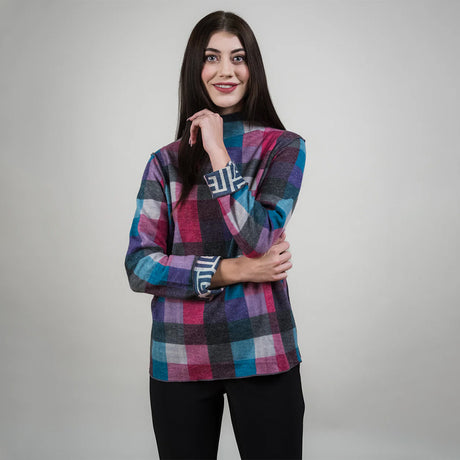 Woman wearing a colorful plaid sweater on a gray background